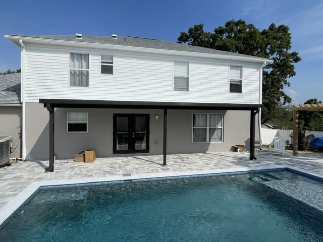 Black aluminum pergola over a paver pool deck